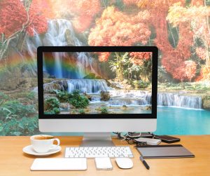 Conceptual image of a workspace with computer desktop on Beautiful waterfall with soft focus and rainbow in the forest