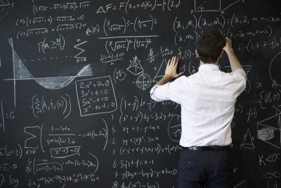 man writing formulas on a chalk board